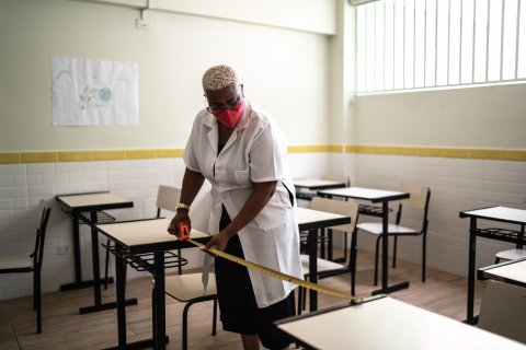 Educator measuring desk spacing for social distance